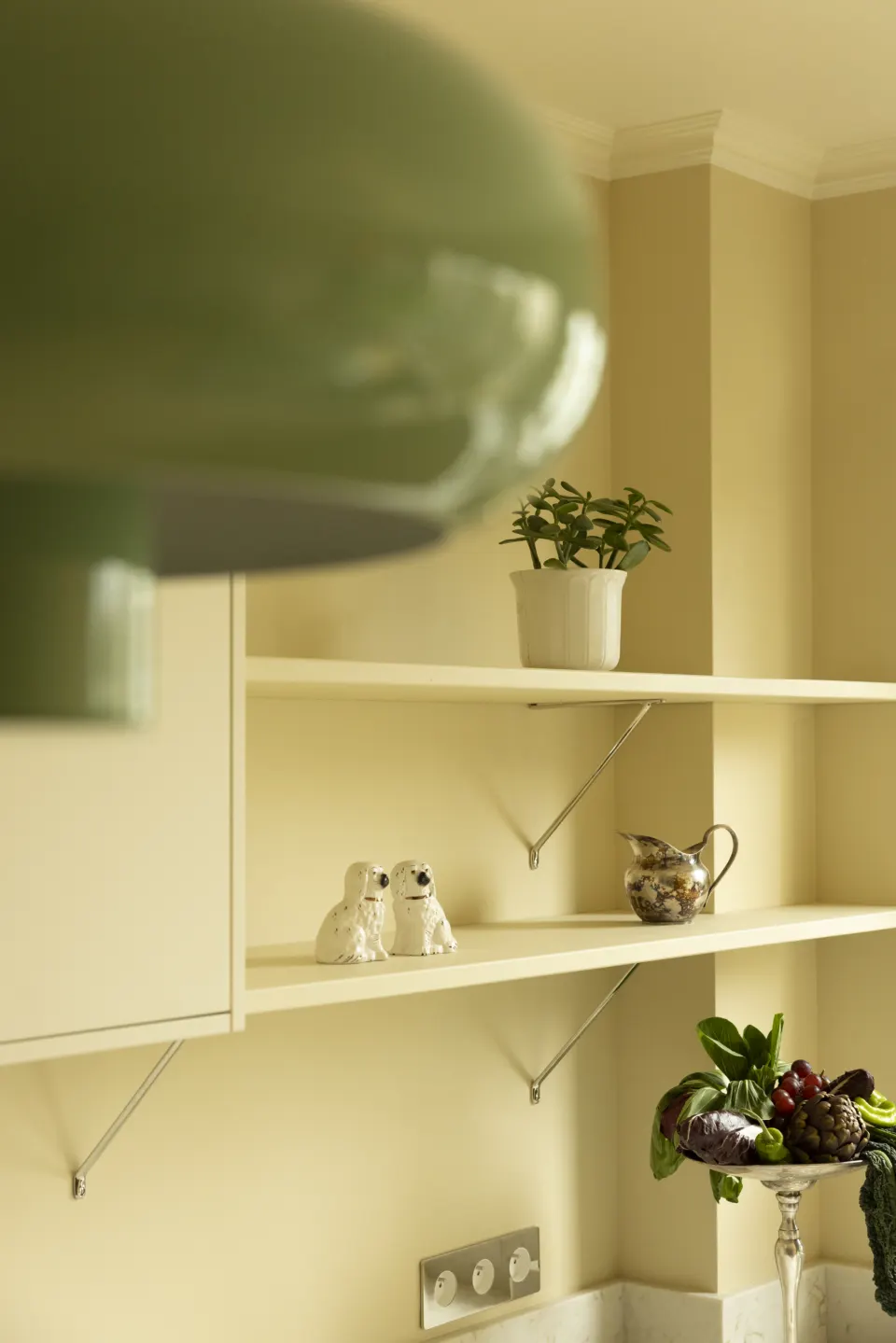 Green glass pendant above a shelf of plants and ceramics