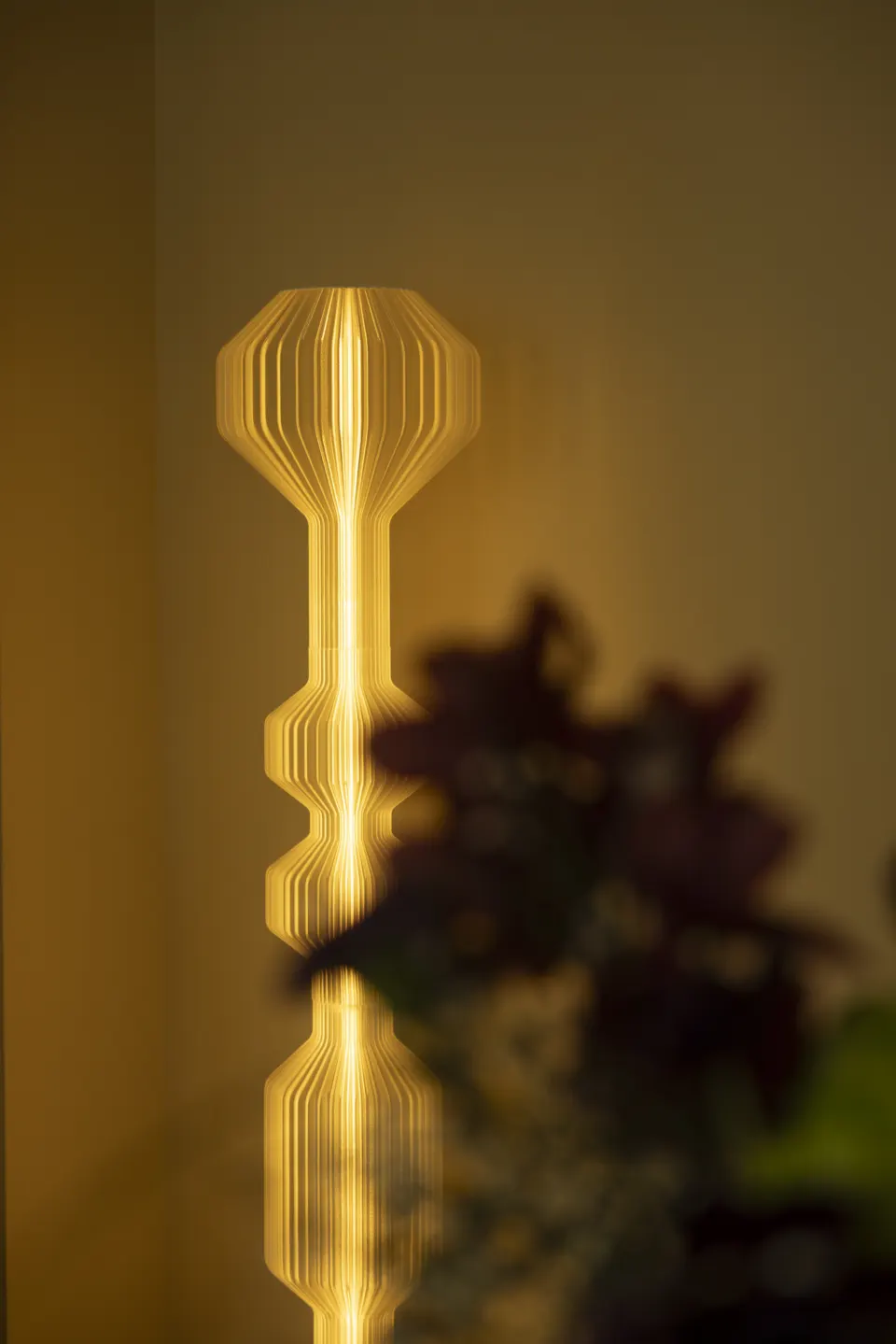 Sculptural amber lamp and backlit foliage