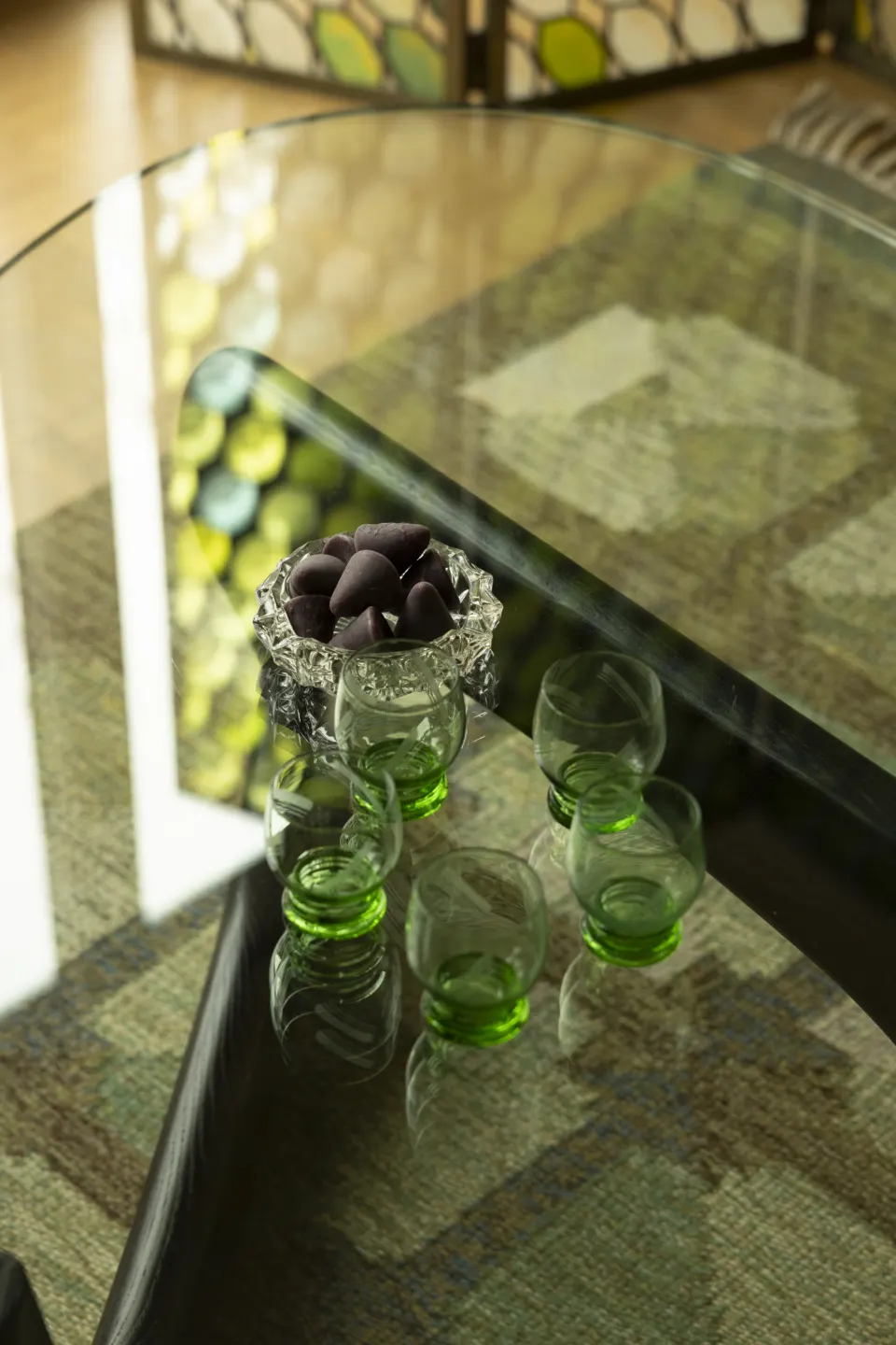 Green glassware and a bowl on a glass coffee table