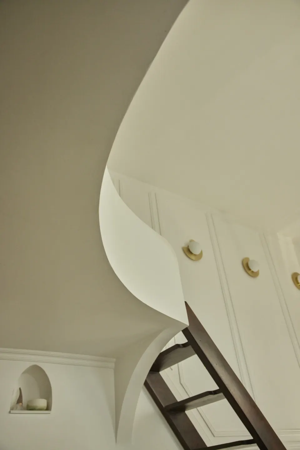 White staircase with soft curves and brass sconces