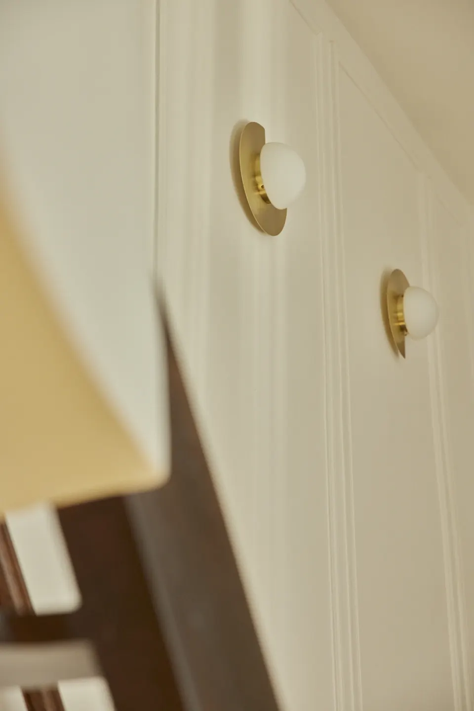 Cream panelled wall and two small brass sconces